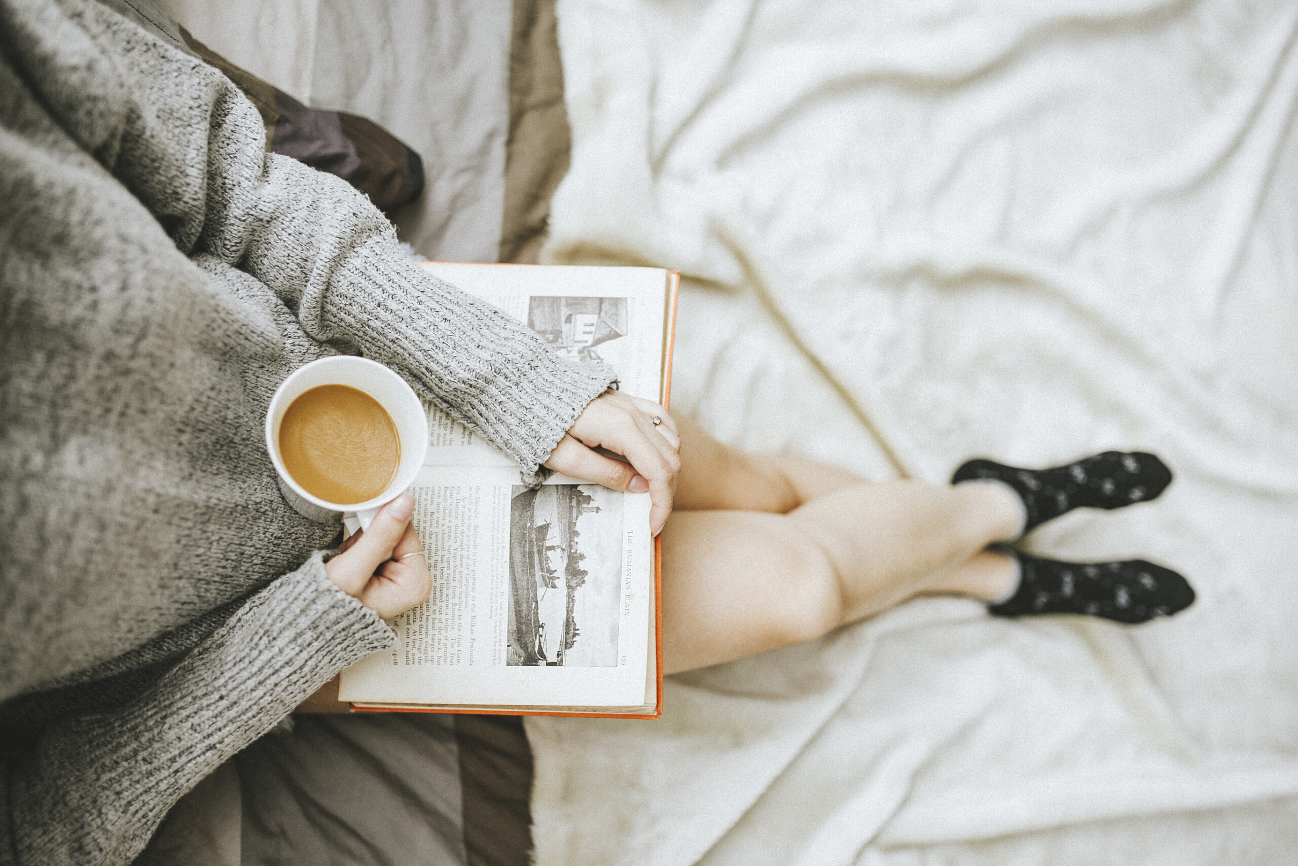 open book with cup of coffee, legs